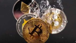 Souvenir tokens representing cryptocurrency networks Bitcoin, Ethereum, Dogecoin and Ripple plunge into water in this illustration (REUTERS)