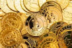 Купа золотих монет із логотипом Bitcoin.